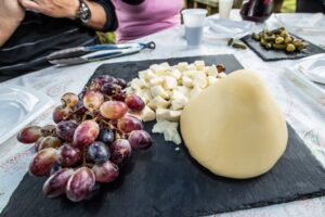 Cheese platter with grapes and diced cheese served on a black slate board during a tasting.