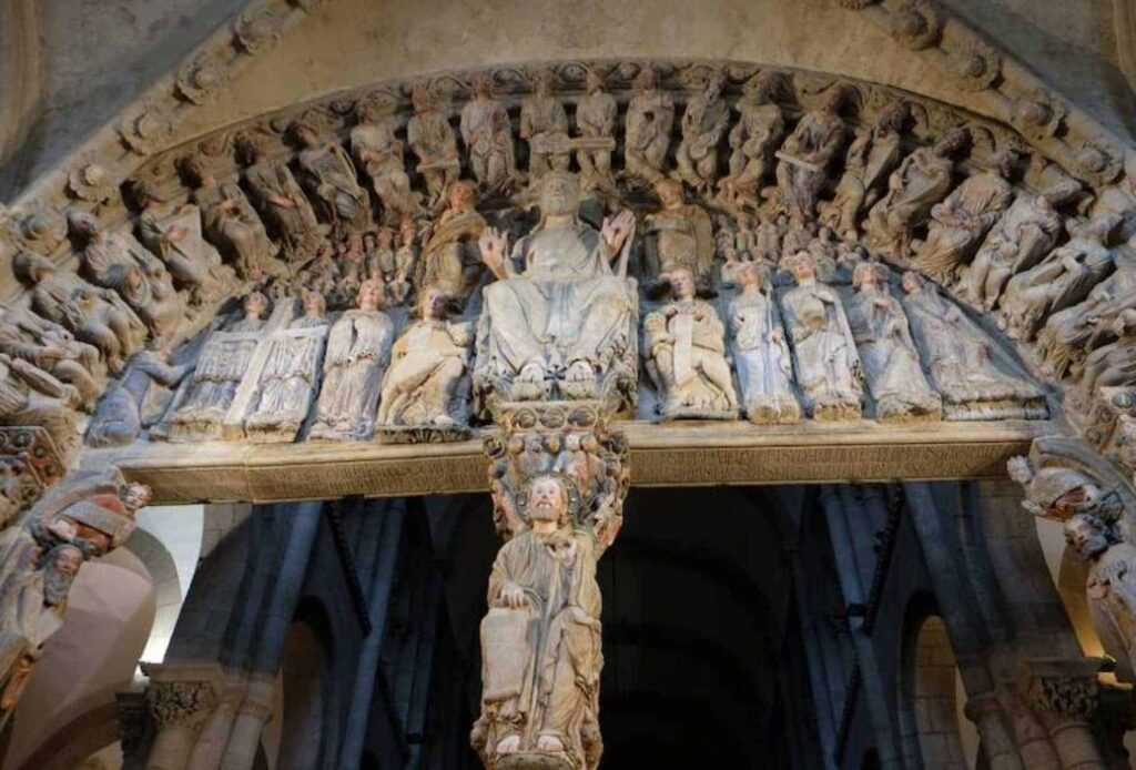 Romanesque stone tympanum depicting Christ in Majesty surrounded by apostles and angels at Santiago de Compostela Cathedral.