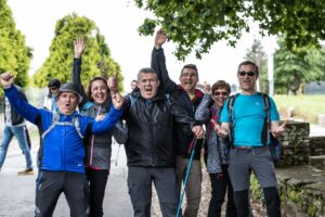 Group of pilgrims cheering together on the Camino de Santiago trail in Galicia, Spain.