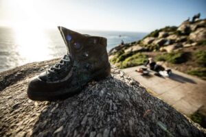 Bronze hiking boot sculpture on a rock overlooking the ocean at Cape Finisterre, Spain.