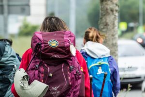 Pilgrims walking with backpacks displaying the yellow scallop shell symbol of the Camino de Santiago.