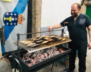 Man grilling sardines over charcoal during the San Juan Festival in Galicia, Spain.